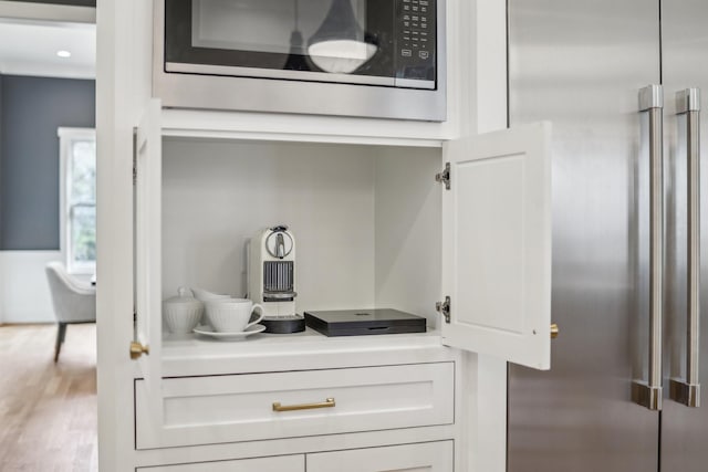 details with built in microwave, hardwood / wood-style floors, high end refrigerator, and white cabinets