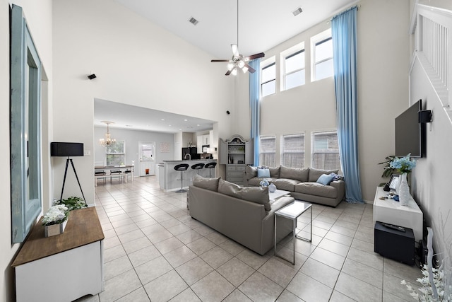 living room with ceiling fan with notable chandelier, a towering ceiling, and light tile patterned flooring