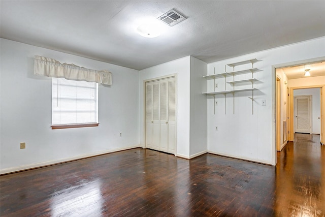 unfurnished bedroom featuring dark hardwood / wood-style flooring and a closet