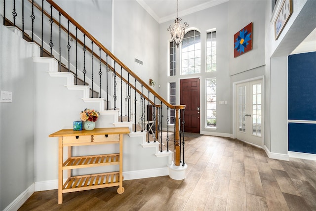 foyer featuring crown molding, french doors, a high ceiling, and a notable chandelier