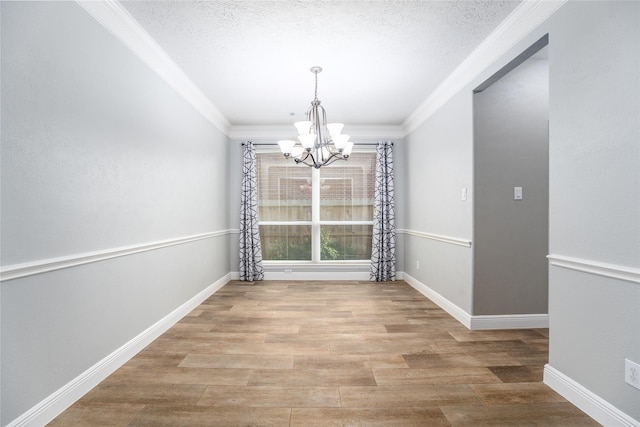 unfurnished dining area with a chandelier, a textured ceiling, light hardwood / wood-style floors, and crown molding