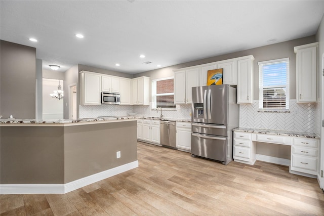 kitchen featuring white cabinetry, sink, pendant lighting, appliances with stainless steel finishes, and light wood-type flooring