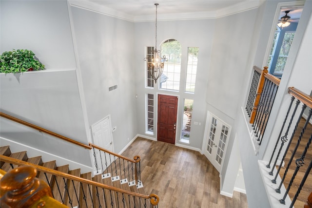 entryway featuring hardwood / wood-style floors, ceiling fan with notable chandelier, a towering ceiling, and ornamental molding