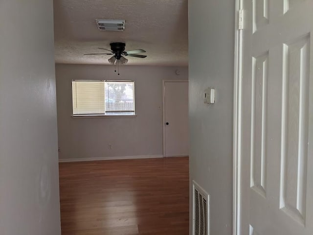 unfurnished room with hardwood / wood-style flooring, ceiling fan, and a textured ceiling