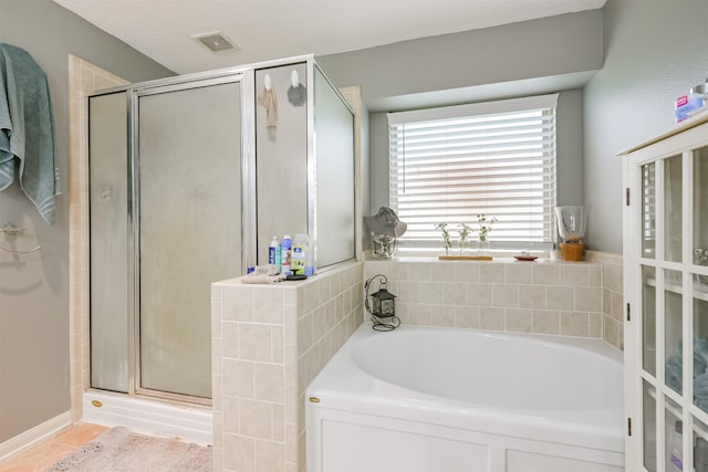 bathroom featuring independent shower and bath and a textured ceiling