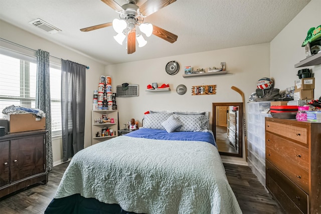 bedroom with ceiling fan, dark hardwood / wood-style floors, and a textured ceiling