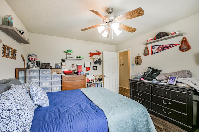 bedroom with a textured ceiling, ceiling fan, and dark wood-type flooring