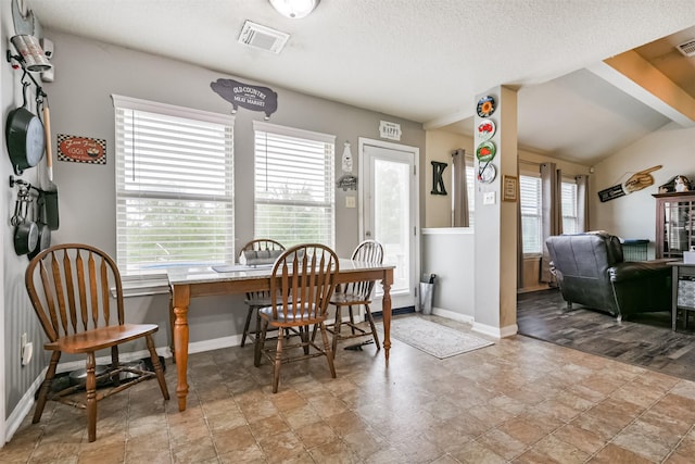 dining room with lofted ceiling and a textured ceiling