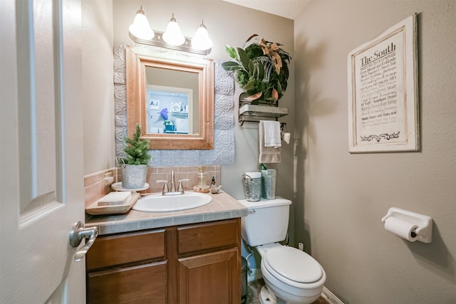 bathroom with decorative backsplash, vanity, and toilet