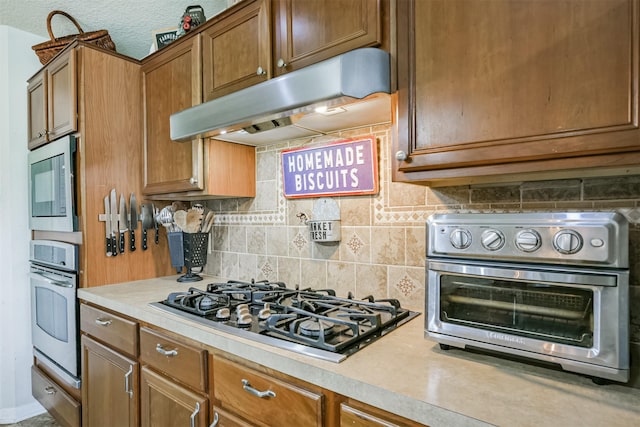 kitchen featuring decorative backsplash, a textured ceiling, and stainless steel appliances