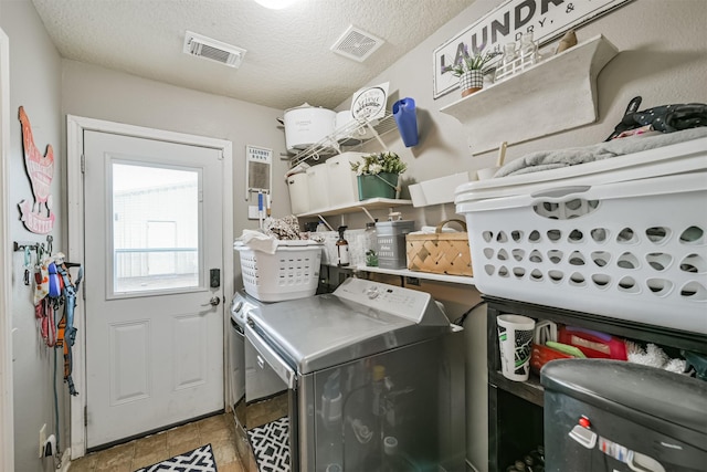 washroom with washing machine and clothes dryer, light tile patterned floors, and a textured ceiling