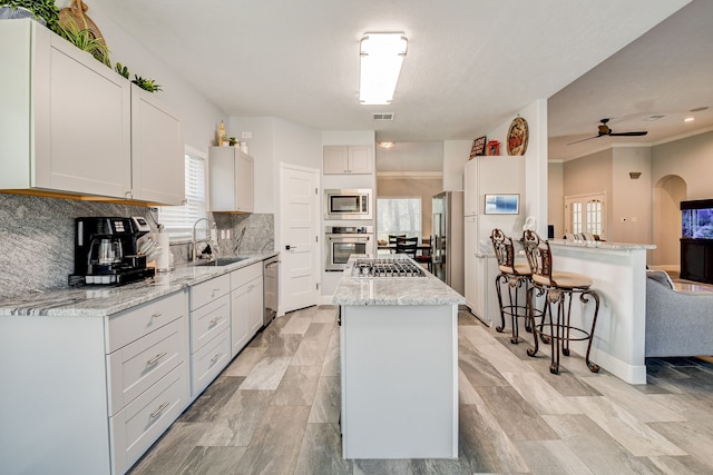 kitchen with appliances with stainless steel finishes, ceiling fan, sink, a center island, and white cabinetry