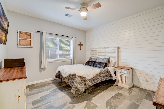 bedroom with ceiling fan and wooden walls