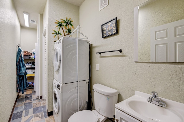 bathroom featuring stacked washer and dryer, vanity, and toilet