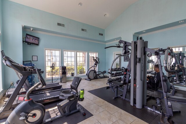 exercise room with light tile patterned floors and high vaulted ceiling