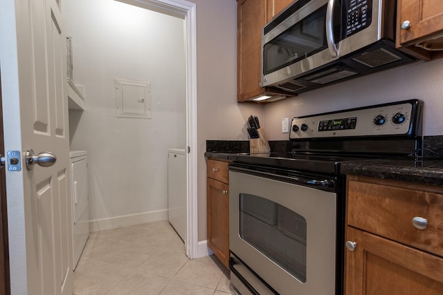 kitchen featuring electric panel, dark stone countertops, light tile patterned floors, and appliances with stainless steel finishes