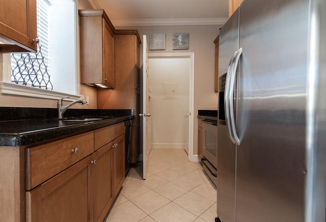 kitchen featuring appliances with stainless steel finishes, dark stone counters, crown molding, sink, and light tile patterned floors