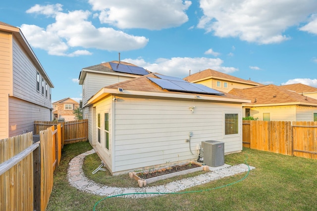 back of property featuring solar panels, a yard, and cooling unit