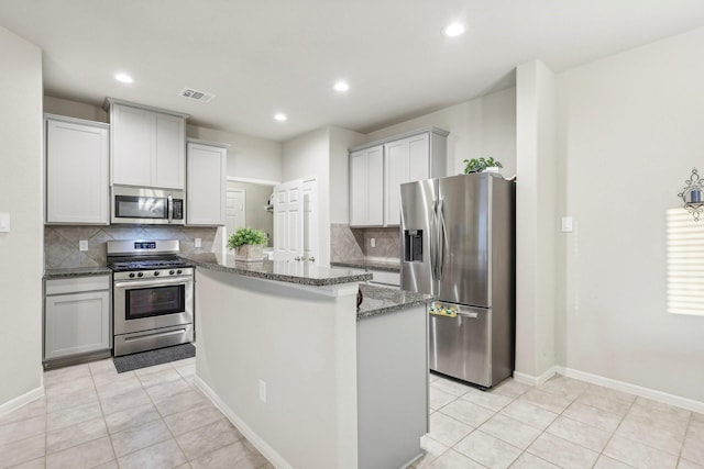 kitchen with backsplash, light tile patterned floors, dark stone counters, and appliances with stainless steel finishes