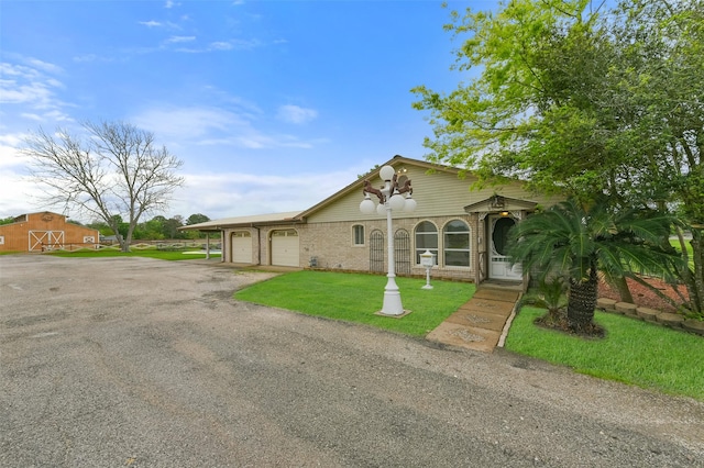 view of front facade featuring driveway, a garage, a front lawn, and brick siding