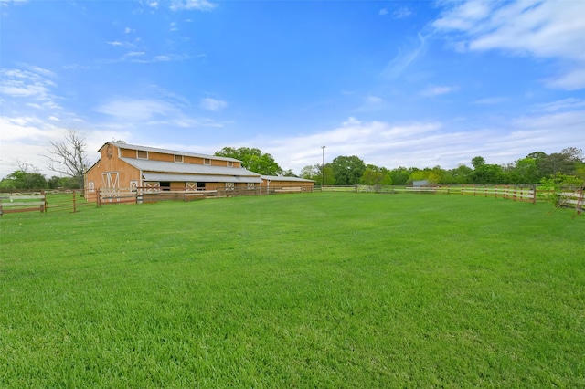 view of yard featuring an outbuilding, a rural view, a barn, and fence