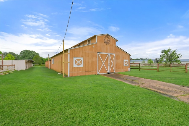 view of barn with a lawn and fence