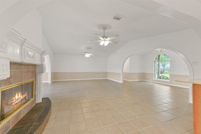 unfurnished living room featuring light tile patterned floors, visible vents, a tiled fireplace, lofted ceiling, and ceiling fan