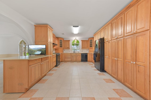 kitchen featuring light countertops, glass insert cabinets, a sink, under cabinet range hood, and black appliances