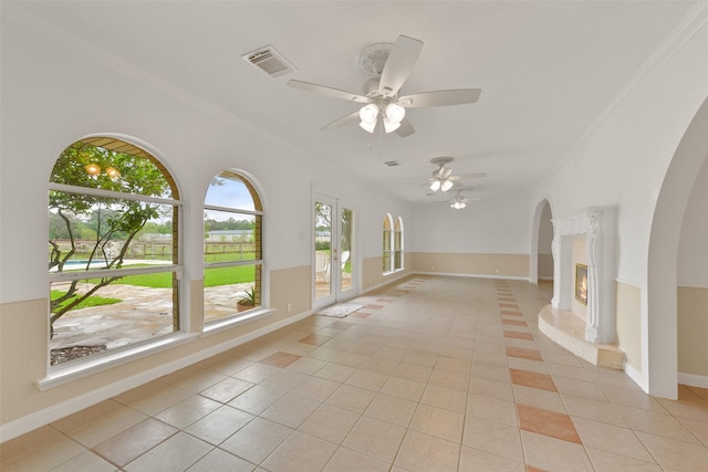 unfurnished living room featuring light tile patterned floors, arched walkways, visible vents, baseboards, and crown molding