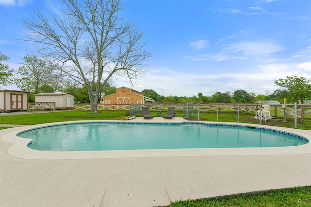 pool featuring a shed, a lawn, an outdoor structure, and fence