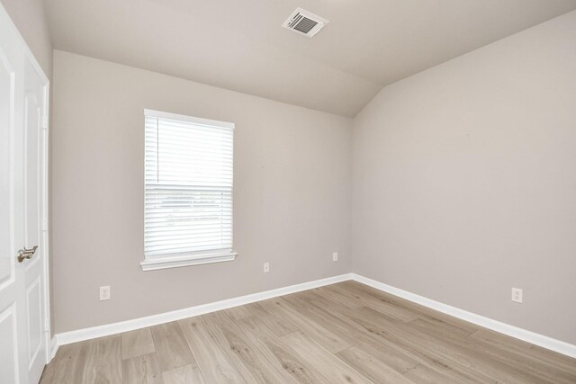 spare room with light hardwood / wood-style flooring and lofted ceiling