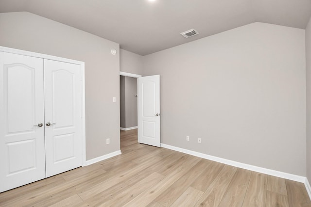 unfurnished bedroom featuring a closet, vaulted ceiling, and light wood-type flooring