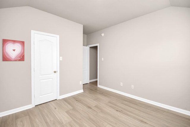 spare room featuring light hardwood / wood-style flooring and lofted ceiling