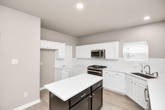 kitchen with stainless steel appliances, sink, a center island, light hardwood / wood-style floors, and white cabinetry