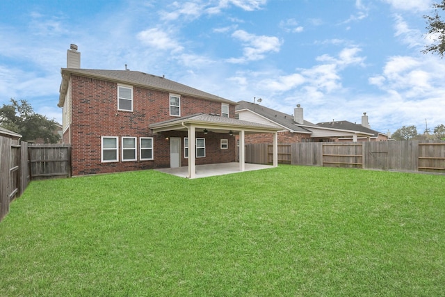 rear view of property with ceiling fan, a patio area, and a lawn