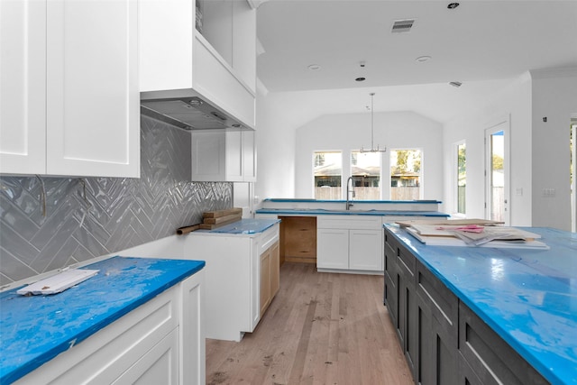 kitchen with sink, light hardwood / wood-style flooring, backsplash, pendant lighting, and white cabinets