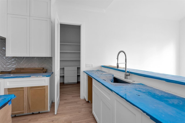 kitchen featuring decorative backsplash, sink, white cabinets, and light hardwood / wood-style floors