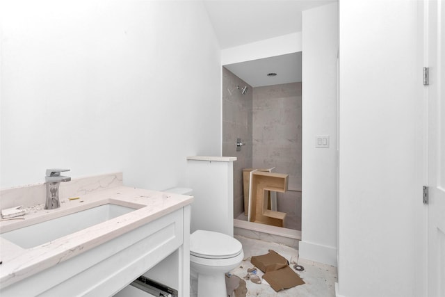 bathroom featuring a tile shower, tile patterned flooring, vanity, and toilet