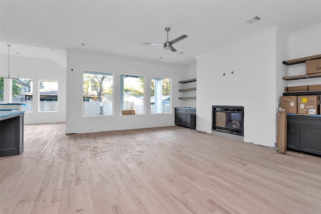 unfurnished living room with ceiling fan, light hardwood / wood-style floors, ornamental molding, and a wealth of natural light