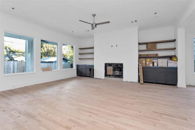 unfurnished living room featuring ceiling fan, light wood-type flooring, and ornamental molding