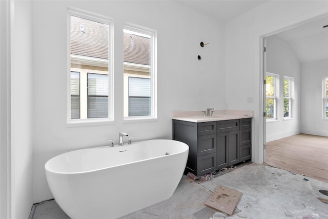 bathroom with a bathing tub, vanity, wood-type flooring, and vaulted ceiling