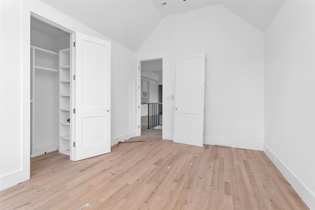 unfurnished bedroom with a spacious closet, lofted ceiling, and light wood-type flooring