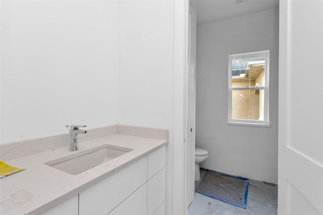 bathroom featuring vanity, concrete flooring, and toilet