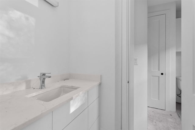 bathroom with vanity, toilet, and concrete floors