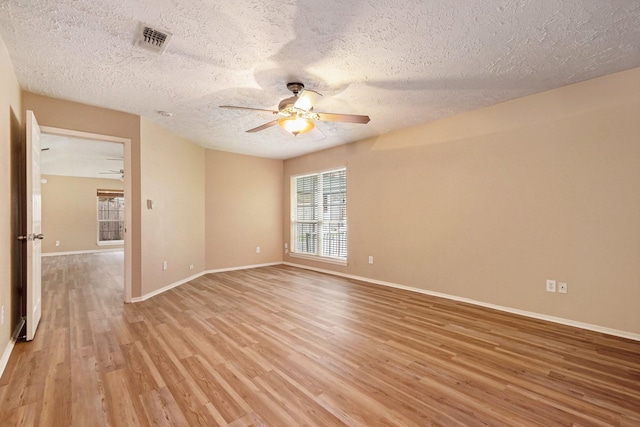 empty room featuring ceiling fan, light wood-type flooring, and a textured ceiling