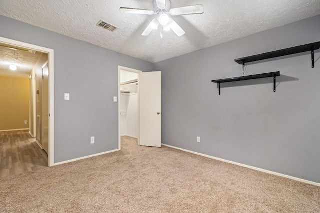 unfurnished bedroom featuring ceiling fan, light colored carpet, and a textured ceiling