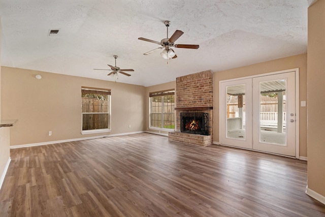 unfurnished living room featuring dark hardwood / wood-style floors, ceiling fan, a textured ceiling, and a brick fireplace