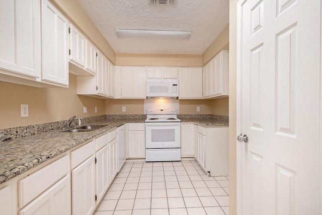 kitchen with a textured ceiling, white appliances, sink, white cabinetry, and light tile patterned flooring