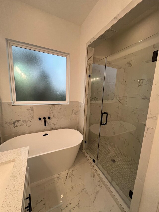 bathroom with shower with separate bathtub, vanity, and tile walls