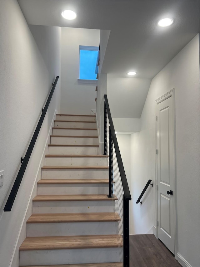 stairway with wood-type flooring and vaulted ceiling